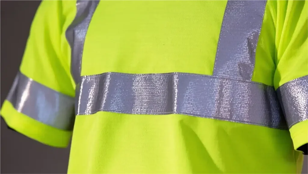 Close-up of reflective safety t-shirt showing detailed reflective strips technology, microscopic glass beads reflecting light, high-visibility fabric texture